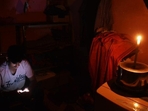 A person using a mobile phone in a candle-lit room during a power outage. (File) A person using a mobile phone in a candle-lit room during a power outage. (File)