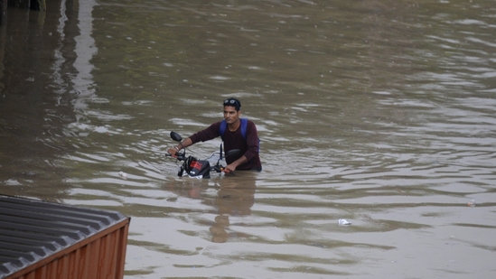 A motorcyclist seen crossing waist-deep water filled stretch in Gurugram on Saturday. (Photo by Parveen Kumar/Hindustan Times)