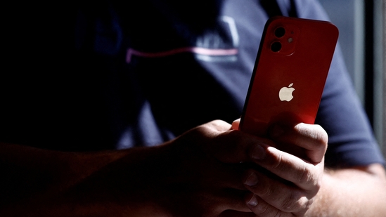 A man poses with an Apple iPhone 12 in a mobile phone store in Nantes, France.(REUTERS)