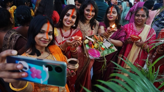 Women observing Chhath rituals near Brahamand Lake, Ghodbander Road in Thane, capturing a selfie on Sunday.(Praful Gangude/HT Photo)