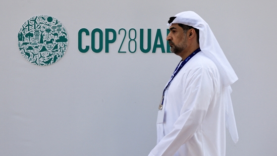 A delegate walks past a logo of the COP28 climate summit in Dubai, United Arab Emirates.(REUTERS)