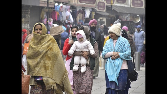 People dressed in warm clothes on a cloudy day in Amritsar on Sunday. (Sameer Sehgal/HT)