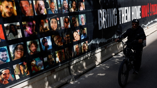 A person rides a bicycle past photos of hostages who were kidnapped in the deadly October 7 attack on Israel by the Palestinian Islamist group Hamas from Gaza, in Tel Aviv, Israel March 6, 2024. REUTERS/Carlos Garcia Rawlins(REUTERS)