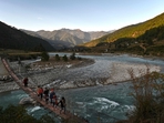 (FILES) This photograph taken on December 6, 2019 shows tourists walking across a suspension bridge over the Puna Tsang Chhu River in Punakha province in Bhutan. Squeezed between giant arch-rivals India and China, the landlocked mountain kingdom of Bhutan was long isolated by icy Himalayan peaks. But as Bhutan readies to elect a new parliament in Thimphu on January 9, China and India are watching the contest with keen interest as they eye strategic contested border zones, analysts warn. (Photo by Lillian SUWANRUMPHA / AFP)(AFP) (FILES) This photograph taken on December 6, 2019 shows tourists walking across a suspension bridge over the Puna Tsang Chhu River in Punakha province in Bhutan. Squeezed between giant arch-rivals India and China, the landlocked mountain kingdom of Bhutan was long isolated by icy Himalayan peaks. But as Bhutan readies to elect a new parliament in Thimphu on January 9, China and India are watching the contest with keen interest as they eye strategic contested border zones, analysts warn. (Photo by Lillian SUWANRUMPHA / AFP)(AFP)