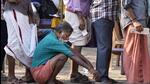 A man squats to rest as people queue up to vote during the second round of voting near Palakkad (AP) A man squats to rest as people queue up to vote during the second round of voting near Palakkad (AP)