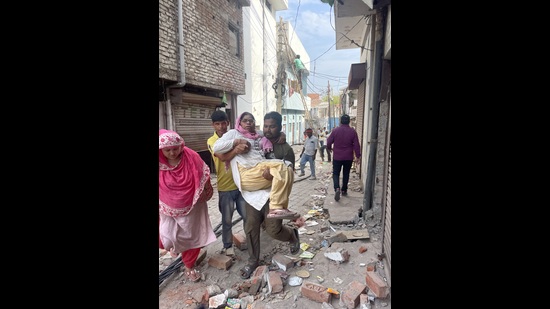 Mohammed Ahmed, a resident, helps his ailing mother move amid a demolition exercise in Akbar Nagar (HT) Mohammed Ahmed, a resident, helps his ailing mother move amid a demolition exercise in Akbar Nagar (HT)