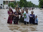 A family wades through a flooded road following heavy rainfall in Ahmedabad, Gujarat. (AP Photo)(HT_PRINT) A family wades through a flooded road following heavy rainfall in Ahmedabad, Gujarat. (AP Photo)(HT_PRINT)