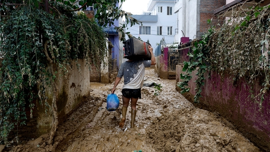 A man walks on a muddy alleyway carrying belongings salvaged from his house in Kathmandu, Nepal, Monday, Sept. 30, 2024 in the aftermath of a flood caused by heavy rains. (AP Photo/Gopen Rai)(AP) A man walks on a muddy alleyway carrying belongings salvaged from his house in Kathmandu, Nepal, Monday, Sept. 30, 2024 in the aftermath of a flood caused by heavy rains. (AP Photo/Gopen Rai)(AP)