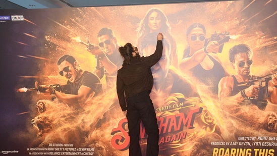 Ranveer Singh admires the poster for Singham Again at the trailer launch in Mumbai. His wife actor Deepika Padukone is also part of the movie but wasn't part of the launch.