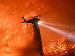 A fire fighting helicopter drops water as the Palisades fire grows near the Mandeville Canyon neighborhood and Encino, California, on January 11, 2025. The Palisades Fire, the largest of the Los Angeles fires, spread toward previously untouched neighborhoods January 11, forcing new evacuations and dimming hopes that the disaster was coming under control. Across the city, at least 16 people have died as multiple fires have ripped through residential areas since January 7, razing thousands of homes in destruction that US President Joe Biden likened to a A fire fighting helicopter drops water as the Palisades fire grows near the Mandeville Canyon neighborhood and Encino, California, on January 11, 2025. The Palisades Fire, the largest of the Los Angeles fires, spread toward previously untouched neighborhoods January 11, forcing new evacuations and dimming hopes that the disaster was coming under control. Across the city, at least 16 people have died as multiple fires have ripped through residential areas since January 7, razing thousands of homes in destruction that US President Joe Biden likened to a