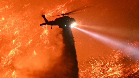 A fire fighting helicopter drops water as the Palisades fire grows near the Mandeville Canyon neighborhood and Encino, California, on January 11, 2025. The Palisades Fire, the largest of the Los Angeles fires, spread toward previously untouched neighborhoods January 11, forcing new evacuations and dimming hopes that the disaster was coming under control. Across the city, at least 16 people have died as multiple fires have ripped through residential areas since January 7, razing thousands of homes in destruction that US President Joe Biden likened to a "war scene." (Photo by Patrick T. Fallon / AFP)(AFP) A fire fighting helicopter drops water as the Palisades fire grows near the Mandeville Canyon neighborhood and Encino, California, on January 11, 2025. The Palisades Fire, the largest of the Los Angeles fires, spread toward previously untouched neighborhoods January 11, forcing new evacuations and dimming hopes that the disaster was coming under control. Across the city, at least 16 people have died as multiple fires have ripped through residential areas since January 7, razing thousands of homes in destruction that US President Joe Biden likened to a "war scene." (Photo by Patrick T. Fallon / AFP)(AFP)