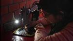 A woman uses her phone’s flashlight to practice sewing at the centre on Friday. (Vipin Kumar/HT Photo) A woman uses her phone’s flashlight to practice sewing at the centre on Friday. (Vipin Kumar/HT Photo)