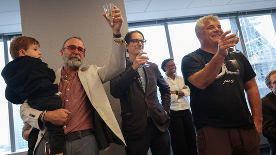 Reuters journalist Maurice Tasman holding his grandson Levi, Global Enterprise Editor Mike Williams and Senior Photographer Shannon Stapleton toast together after the Reuters staff was awarded a Pulitzer Prize in the Investigative Reporting category.(REUTERS)