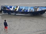 A Del Mar lifeguard looks over a capsized boat on the beach Monday at Torrey Pines State beach in San Diego, California.(AP) A Del Mar lifeguard looks over a capsized boat on the beach Monday at Torrey Pines State beach in San Diego, California.(AP)