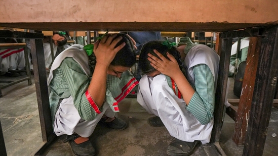 School students crouch under a desk during a drill conducted as part of a nationwide civil defence exercise, in Ghaziabad on Wednesday.(PTI) School students crouch under a desk during a drill conducted as part of a nationwide civil defence exercise, in Ghaziabad on Wednesday.(PTI)