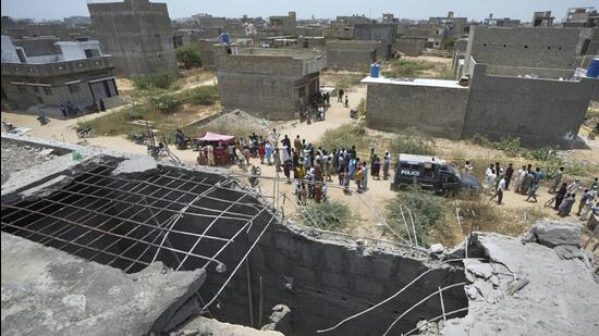 A big hole is seen on a rooftop of a structure suspected to have been damaged in Indian drone attack as residents gather near a cordoned off site where Pakistan's air defence system shot down a suspected Indian drone in Karachi on May 8 (AP) A big hole is seen on a rooftop of a structure suspected to have been damaged in Indian drone attack as residents gather near a cordoned off site where Pakistan's air defence system shot down a suspected Indian drone in Karachi on May 8 (AP)